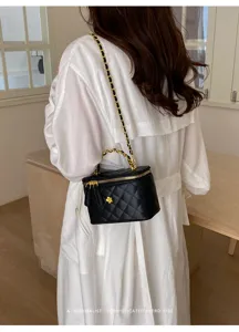 Detail view of the black quilted chain vanity bag with elegant gold hardware and flower.