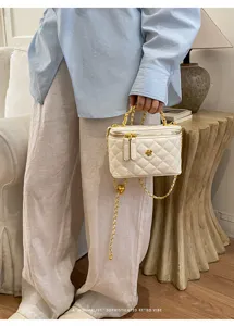 Chic white quilted vanity crossbody bag featuring gold chain strap and exquisite floral accent detail