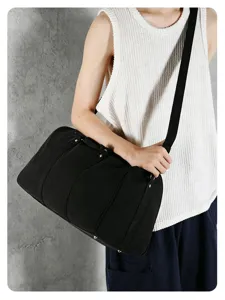 Detail view of a black canvas travel duffel bag, showing shoulder strap and daily use.