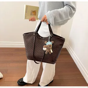 Detailed view of large woven leather tote bag in dark brown with cute bear pendant.