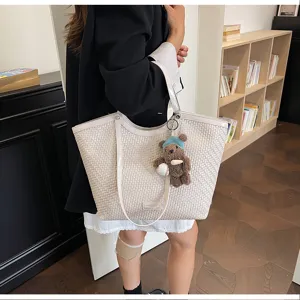Details of the stylish woven tote bag with cute bear charm, perfect for daily commuting.
