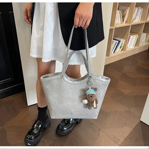 Detailed view of grey woven tote bag featuring large capacity, dual handles and cute bear charm.