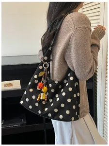 Detailed shot of casual black polka dot tote bag with colorful charm for women daily commuting.