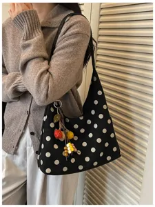 Detailed view of the retro black and white polka dot shoulder bag with cute hanging charms.