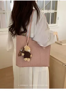 Detailed view of the pink woven shoulder tote bag with cute bear charm and clean interior.