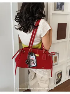 Vista dettagliata di un'elegante borsa a tracolla vintage rossa con doppi manici e ciondolo.