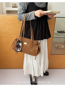 Dettaglio borsa a spalla marrone vintage, elegante shopper da donna con doppi manici e ciondolo chic.