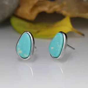 Gros plan détaillé de boucles d'oreilles clous en turquoise poire avec monture en argent.