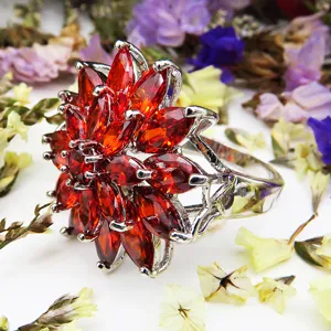 Gedetailleerde close-up van een rode zirkonia bloem statement ring met zilveren zetting.