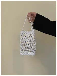 Dettaglio borsa mini intrecciata con conchiglie macramè, corda bianca e perle vicine.