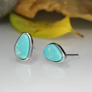 Gros plan détail de boucles d'oreilles en turquoise irrégulière montrant la texture unique de la pierre.