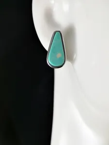 Vue de détail en gros plan de boucles d'oreilles puces turquoise en forme de goutte en argent.
