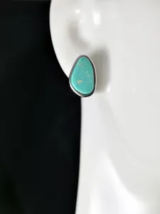 Détail de boucle d'oreille clou turquoise géométrique avec texture naturelle et argent.