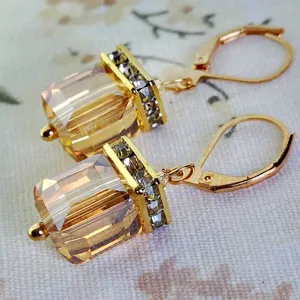 Vista detallada de pendientes colgantes cuadrados de cristal dorado vintage con brillantes pedrería.