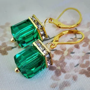 Vista detallada de pendientes colgantes de cristal verde con pedrería, estilo vintage.