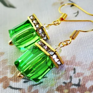 Primer plano detallado de pendientes bloque cristal verde con barra de estrás, joyería.