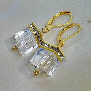 Vista detallada de pendientes cuadrados de cristal minimalistas con cierre dorado elegante.