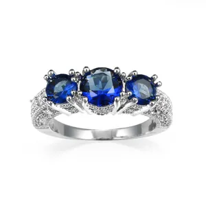 Detailaufnahme des glänzenden blauen Zirkon-Dreisteinrings mit filigranem Pavé-Besatz.