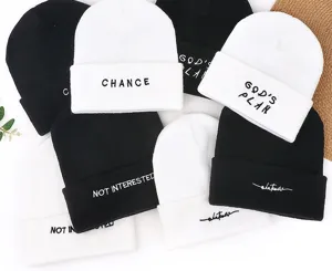 Detailed view of winter knit beanie hats with embroidered text in black and white styles.