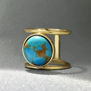 Vue rapprochée d'une bague double anneau dorée avec accent en pierre turquoise ronde.