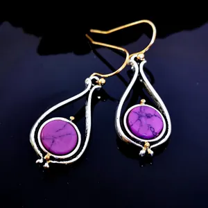 Close-up detail of purple turquoise two-tone dangle earrings with gold and silver finish.