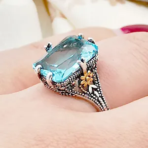 Detailed close-up of vintage Thai silver gemstone ring with blue topaz and floral motif.