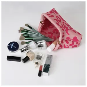 Detailed view of pink knit cosmetic pouch with leopard pattern and makeup brush set.