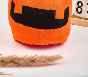Detailed shot of orange knit Halloween pumpkin beanie hat, warm embroidered winter cap.