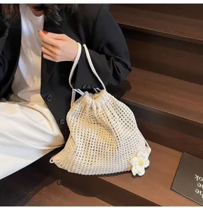 Vue détaillée d'un sac seau en filet tricoté couleur écrou avec un joli détail de fleur.