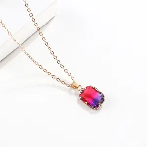 Close-up of a stunning rectangular gradient colored glass gemstone pendant necklace in gold.
