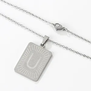 Dettaglio ravvicinato della bellissima collana con ciondolo lettera U in acciaio.