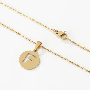 Nahaufnahme einer goldenen Edelstahl Halskette mit rundem Anhänger mit hohlem Buchstaben F.