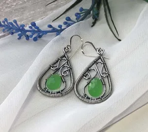 Boucles d'oreilles pendantes en fil d'argent fait main et pierre verte gros plan.