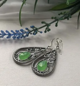 Gros plan de boucles d'oreilles en fil d'argent avec des pierres taillées en forme de goutte.