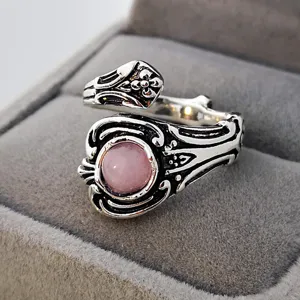Anello vintage in argento con gemma rosa, fascia lavorata, elegante dettaglio di gioiello.