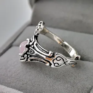 Anello vintage in argento e cristallo rosa in primo piano, design retrò intagliato dettaglio.