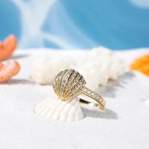 Anello con conchiglia dorata e cristalli scintillanti, gioiello elegante in stile marino.