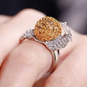 Primo piano dettagliato dell'anello lumaca creativo con zirconi ambra e trasparenti.