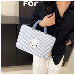 Vista dettagliata della borsa per laptop a quadri blu con toppa di cane bianco.