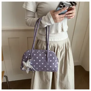 Detailed view of purple polka dot bowling bag with star charm and double shoulder straps.