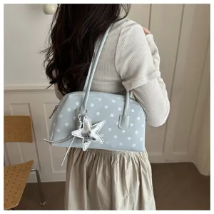 Detailed view of light blue polka dot shoulder bag with silver star charm in daily scene.