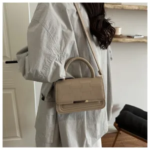 Sac à bandoulière minimaliste pour femme avec surface texturée et poignée supérieure.