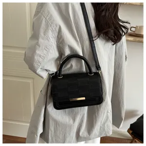Vue détaillée d'un sac à bandoulière noir élégant porté, montrant une texture de qualité.