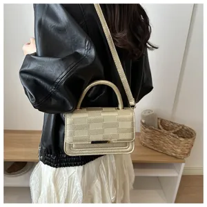 Vue détaillée d'un sac à main doré métallisé avec poignée supérieure et texture quadrillée chic.
