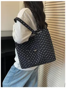 Vue détaillée du sac cabas en toile à pois noirs et blancs porté, montrant la poche avant.