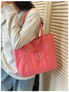 Vue détaillée du sac cabas en toile à pois roses, avec poche avant à cordon et double poignée.