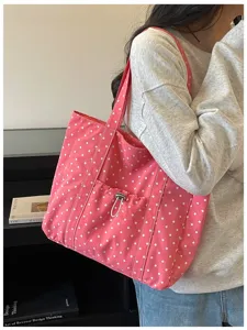 Gros plan sur le cabas en toile à pois roses avec poche avant et cordon de serrage.