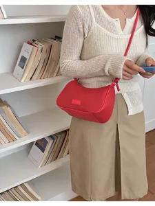 Red woven underarm shoulder bag detail, stylish pillow bag worn by model, chic and trendy accessory.