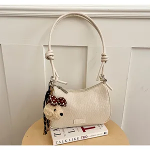 Chic woven shoulder bag with cute puppy plush pendant, versatile neutral cream design.