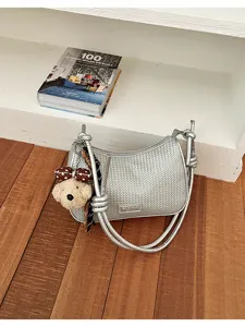 Detailed view of silver woven shoulder bag featuring a cute bear plush pendant and chic handle.